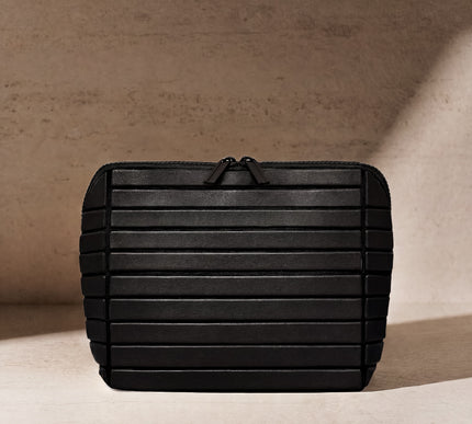Black rectangular pouch with textured surface on a beige background